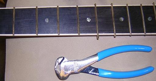 Trimming off the overhanging fret ends.