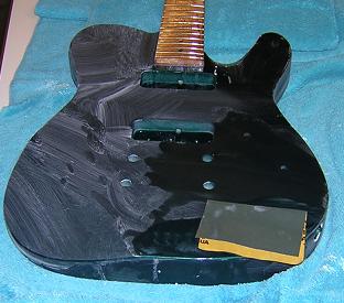 Sanding the front of the guitar with 2000 grit sandpaper.