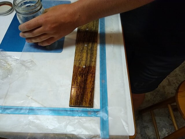 Applying a coat of shellac to the fretboard.