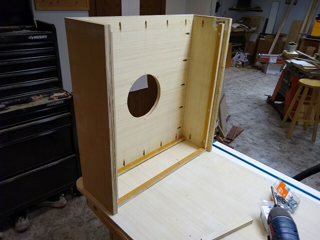 Attaching the subwoofer enclosure to one side of the cabinet.